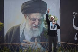 Iránec ukazuje znak víťazstva stojac pred portrétom zabitého vodcu ajatolláha Alího Chameneího v Teheráne 4. marca. Foto: Morteza Nikoubazl/ NurPhoto / Shutterstock Editorial / Profimedia