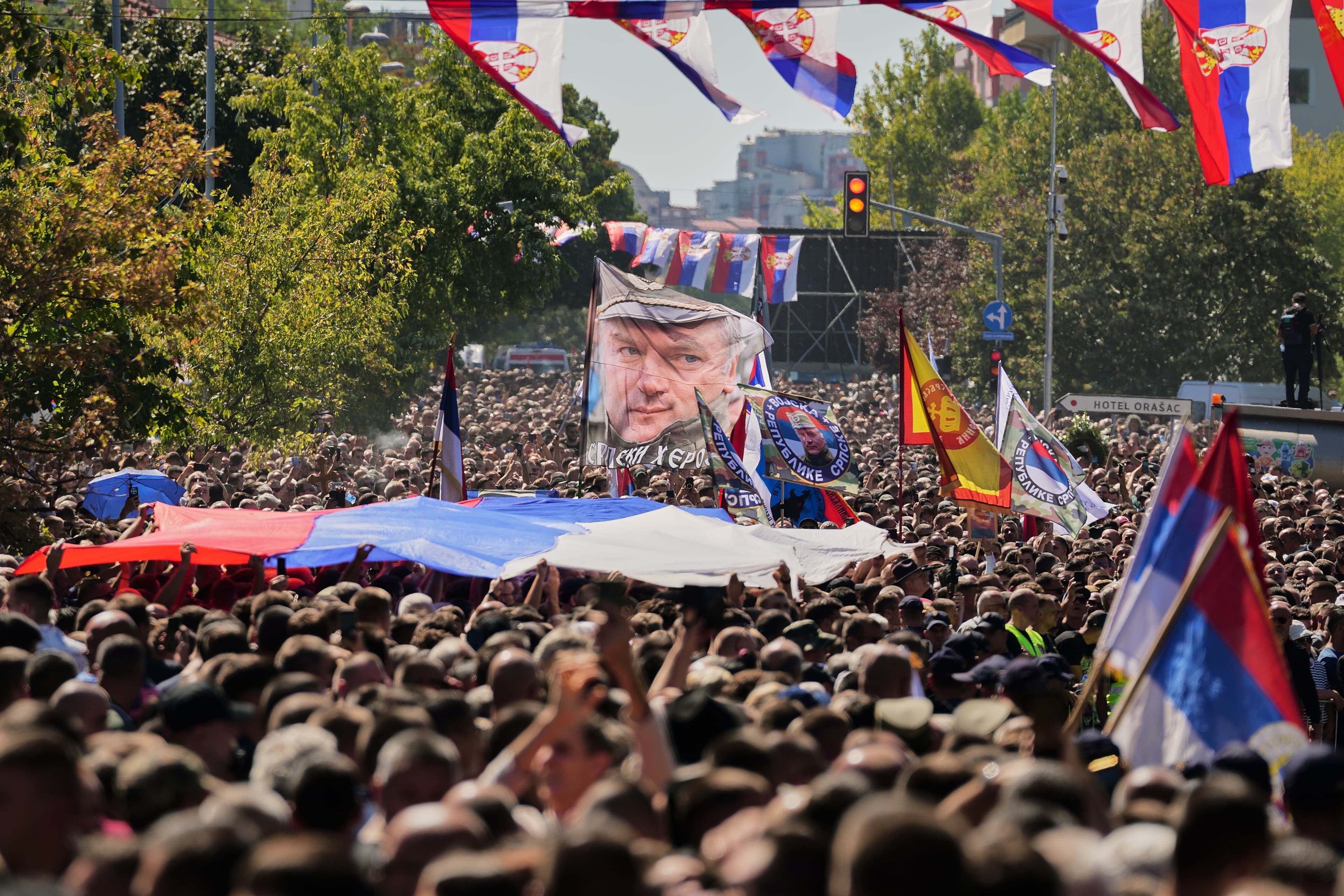 Ľudia mávajú vlajkami s podobizňou vojnového zločinca Ratka Mladiča počas jeho pohrebu v Belehrade. Foto:TASR/AP Photo/Darko Vojinovic